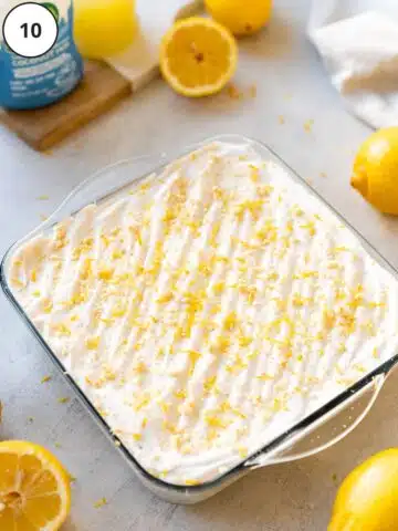 Vegan lemon lush dessert in an 8x8-inch dessert pan after being garnished with a fresh rasping of zest and crushed cookies.
