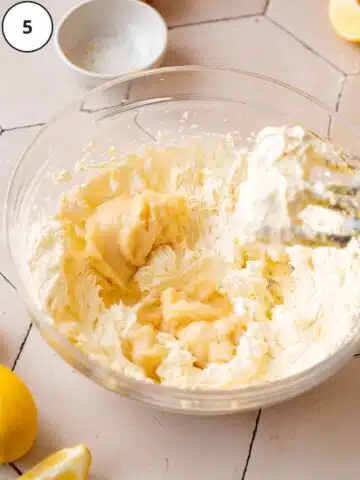 vegan lemon frosting in a mixing bowl with cooled custard being whisked through it.