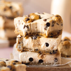 Side on shot of a stack of 3 vegan chocolate chip cookie dough cheesecake bars.