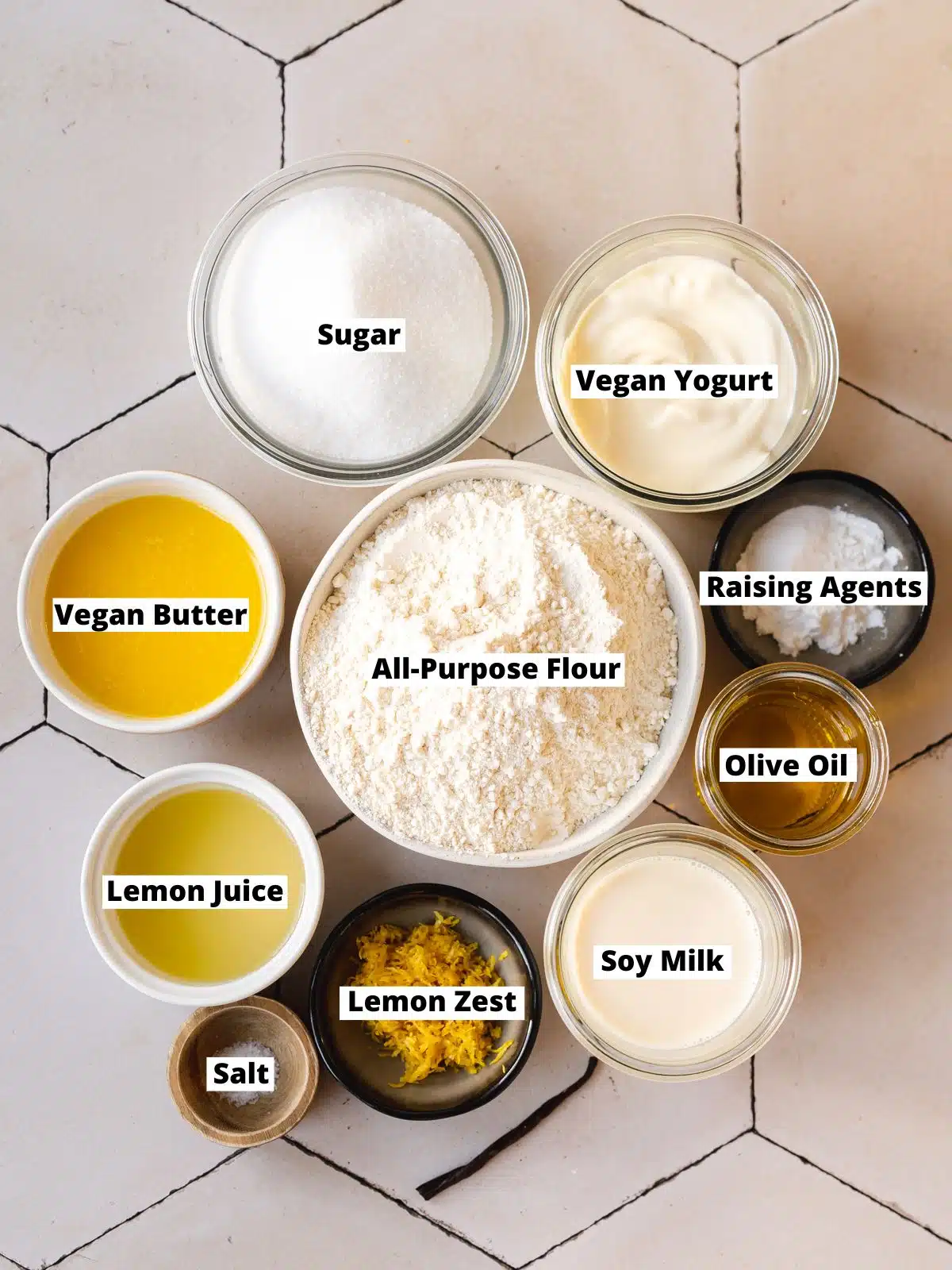 ingredients for easy vegan lemon sheet cake measured out in bowls on a tiled surface.