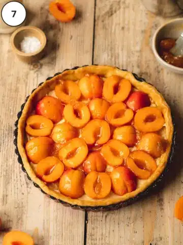 Vegan apricot tart has been assembled with alternating sides of the glazed, halved apricots before baking.
