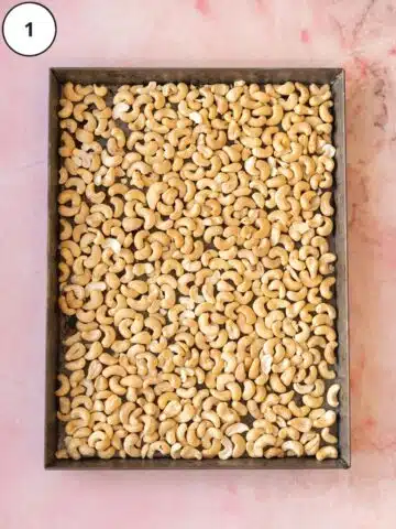 raw cashews laid out on a baking sheet before going into the oven to roast.