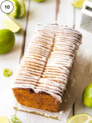 The lime cake has been removed from the tin and neatly drizzled with stripes of lime icing.
