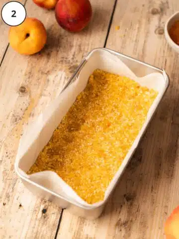 Press-in nut and apricot crust in the base of a parchment-lined loaf tin.