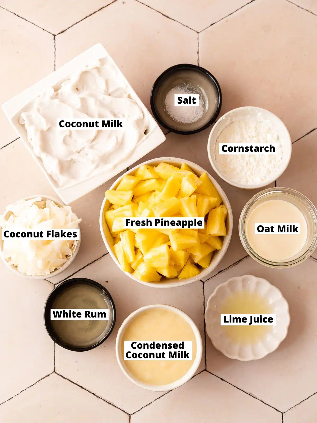 ingredients for pineapple and coconut ice cream measured out in bowls on a tiled surface.