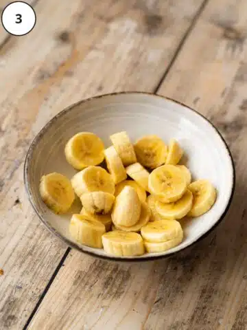 Sliced bananas in a bowl with lemon juice.