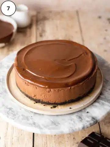 Vegan no-bake chocolate cheesecake after removing from the baking tin and topping with vegan chocolate ganache.