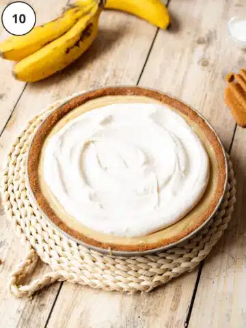 Whipped cream added on top of the banana custard pie.