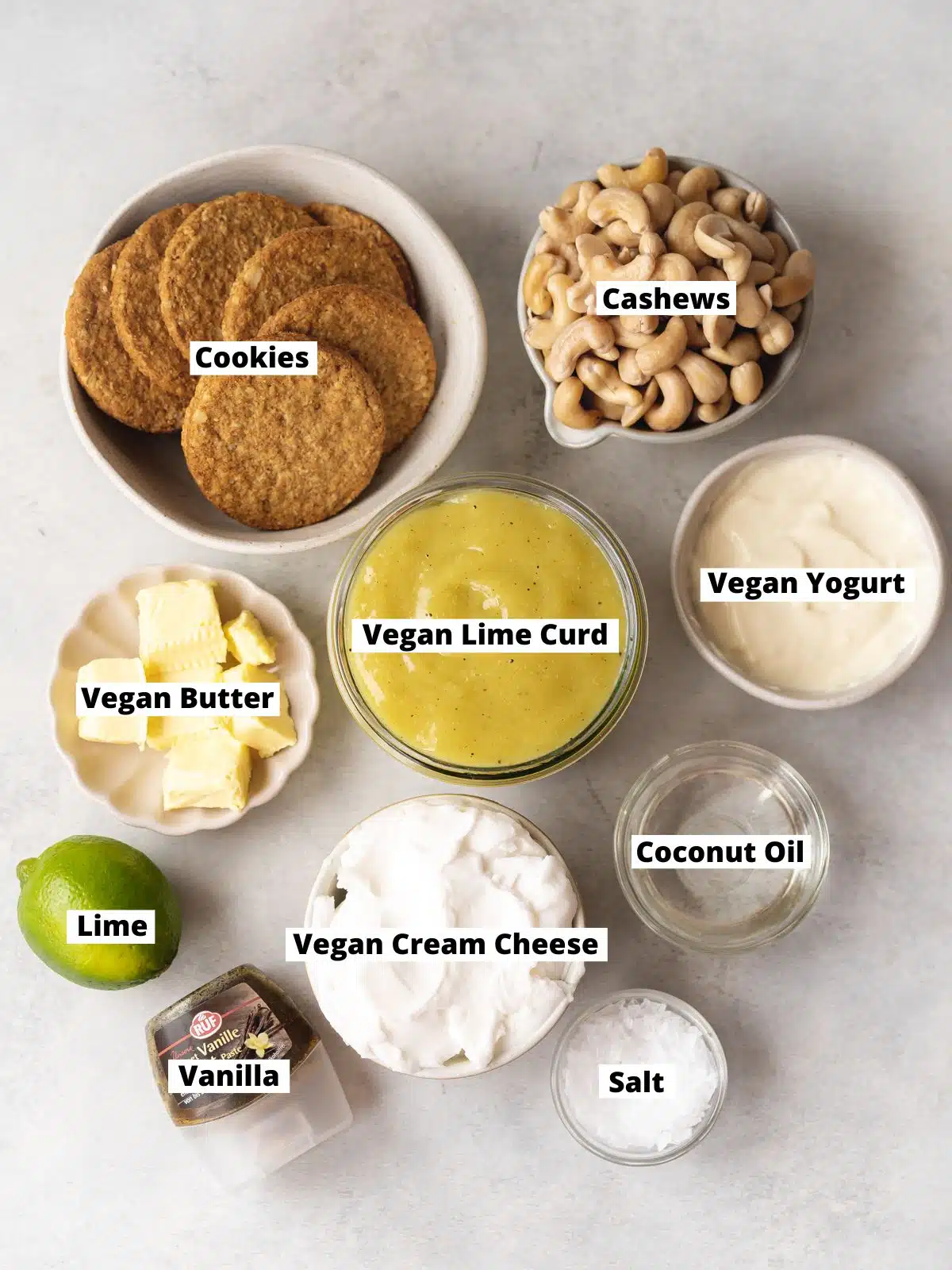 ingredients to make vegan lime cheesecake measured out in small bowls on a gray surface.