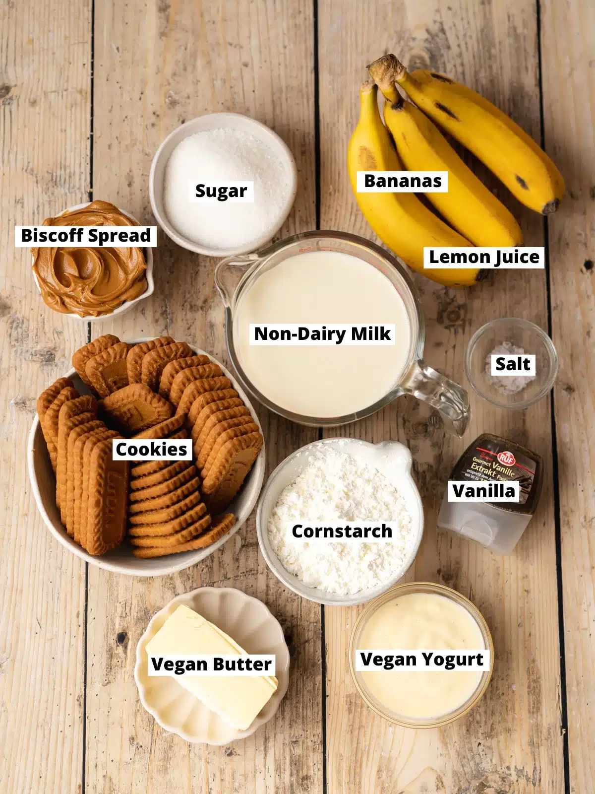 Ingredients needed to make vegan banana cream pie measured out into bowls on a wooden table.