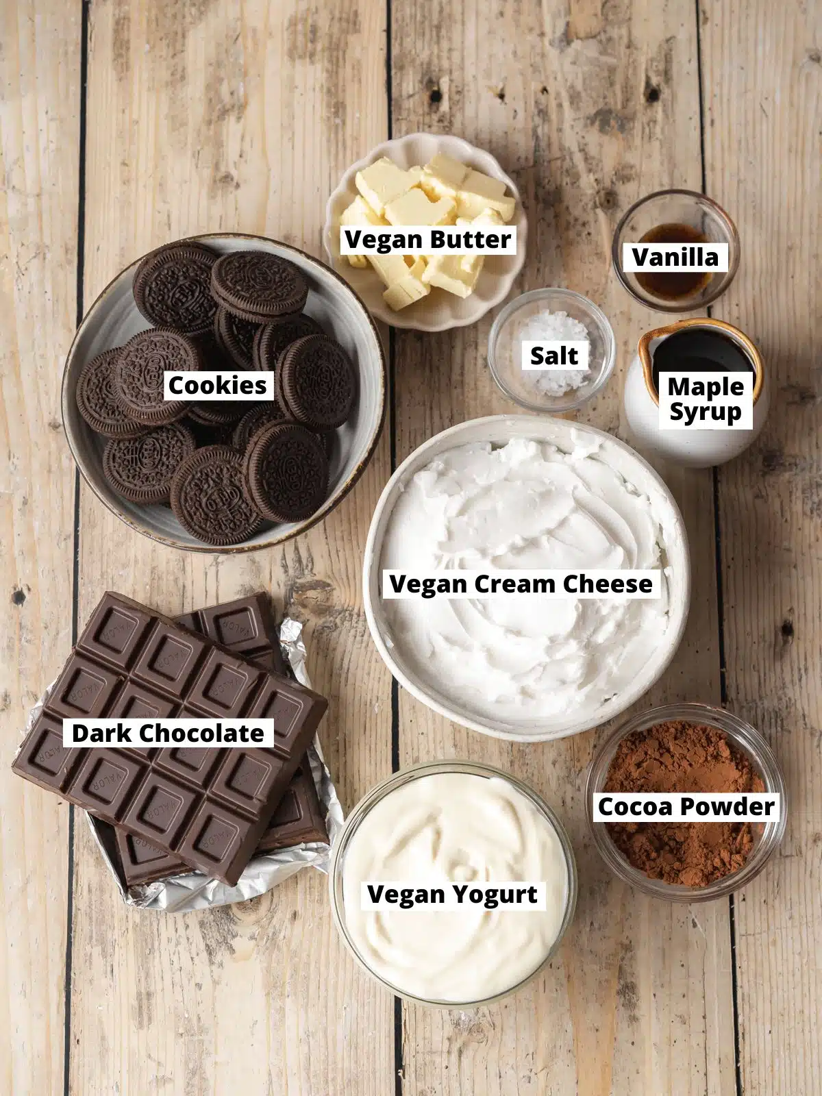 Ingredients needed to make vegan no-bake chocolate cheesecake measured out into bowls on a wooden table.