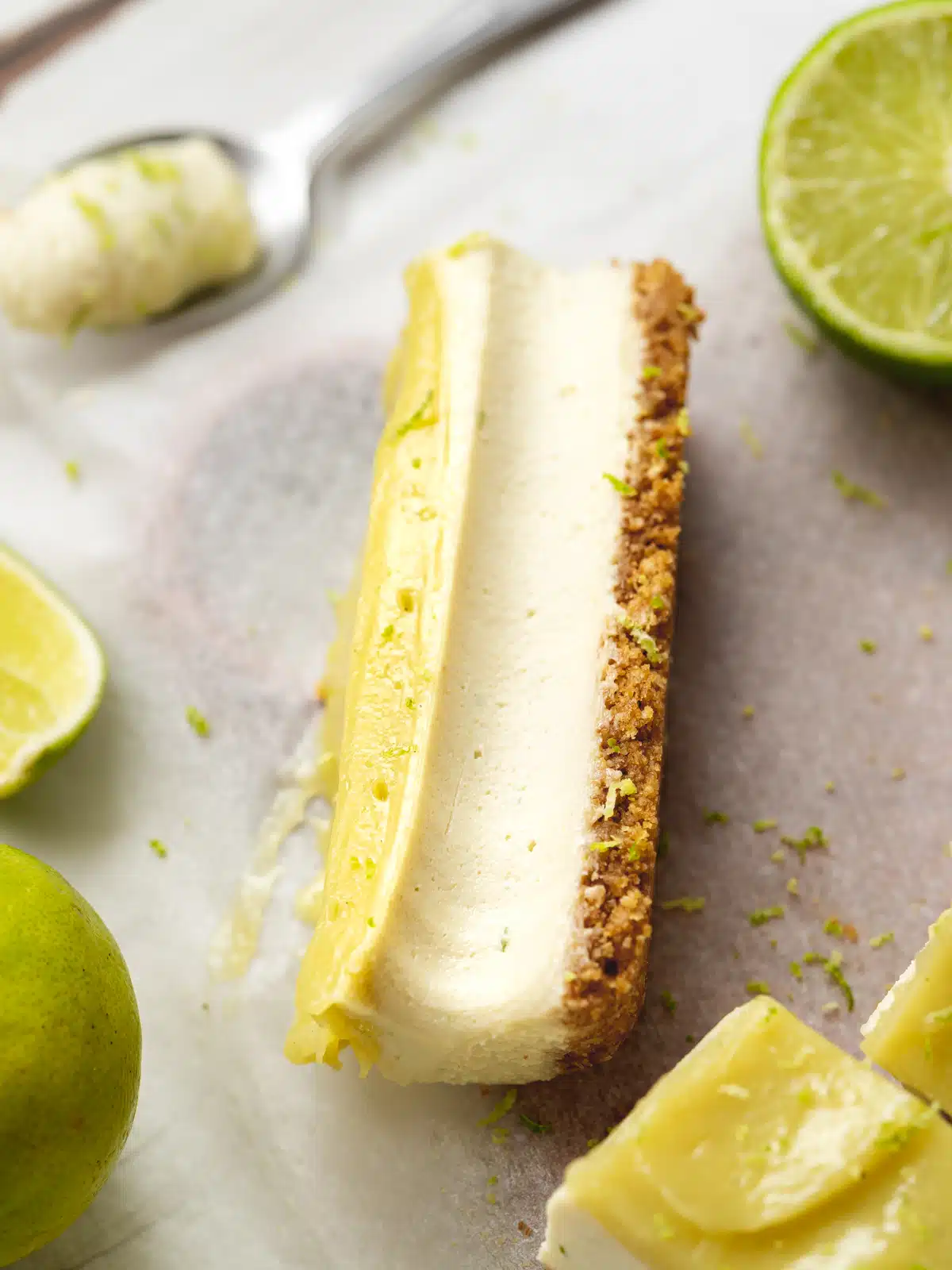 a lime cheesecake bar with lime curd topping and a spoonful of the cheesecake filling scooped out showing the creamy consistency.