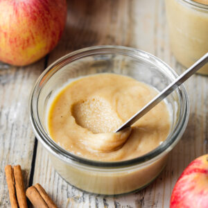 homemade apple curd in a Weck jar with a knife smearing some showing the thick and creamy consistency.