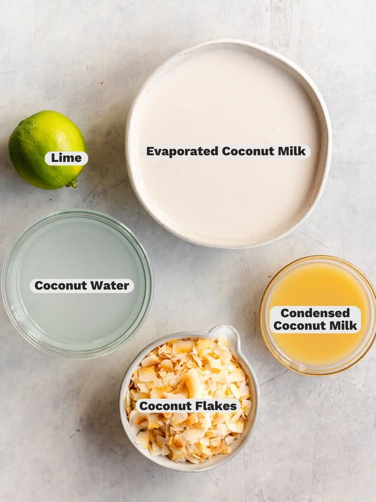 ingredients for vegan coconut sorbet measured out in bowls on a gray surface.