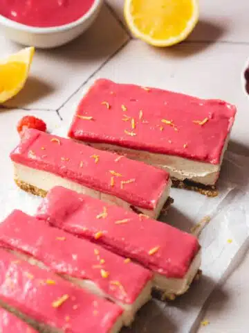 raspberry and lemon cheesecake bars sliced on a sheet of parchment.