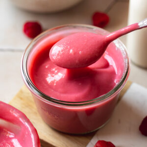 thick raspberry curd in a Weck jar with a spoonful being taken showing the creamy consistency.
