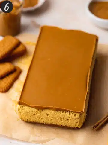 Loaf of biscoff-crusted pumpkin cheesecake bars on a piece of parchment before garnishing or slicing.