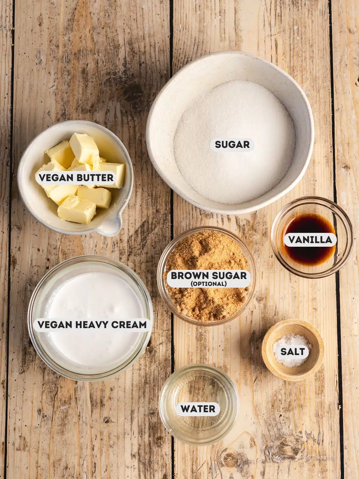 ingredients for vegan caramel sauce measured out in bowls on a wooden table with text overlay.