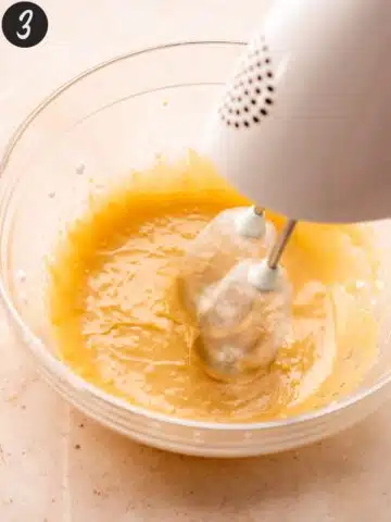 whisking vegan yogurt, sugar, vanilla, and olive oil in a bowl with an electric mixer.