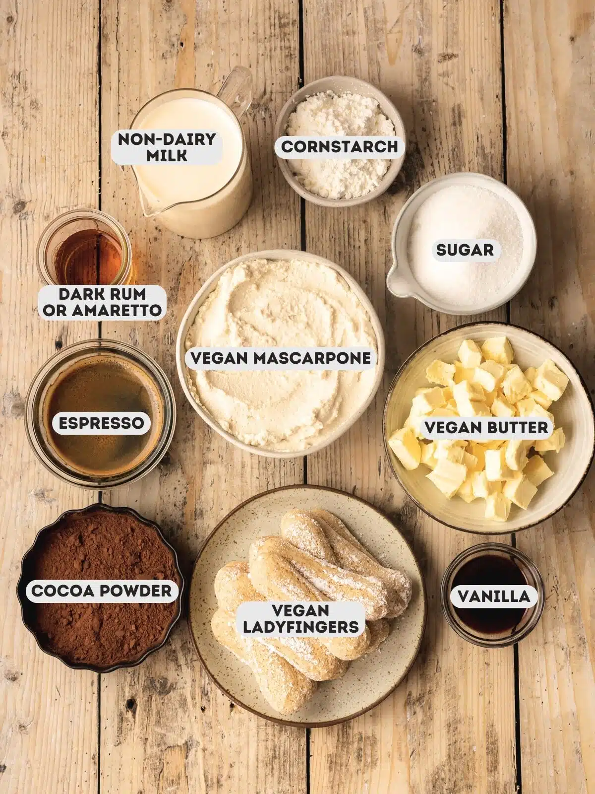 ingredients for vegan tiramisu measured out in bowls on a wooden surface.