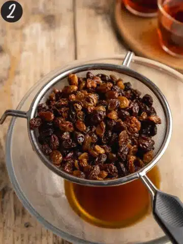 raisins and sultanas draining into a bowl in a fine-mesh sieve.