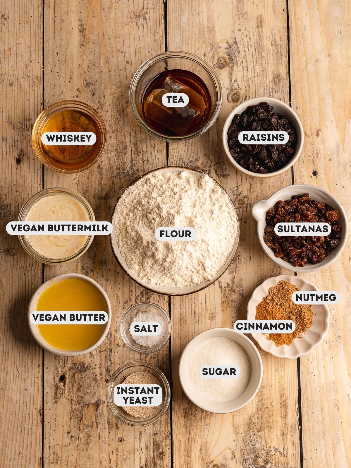 ingredients to make vegan barmbrack measured out in bowls on a wooden table with text overlay.