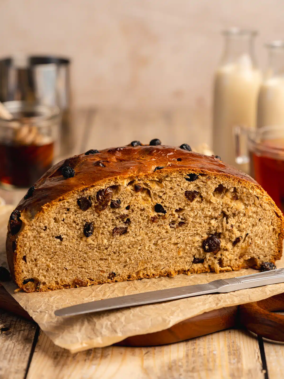 half a loaf of barmbrack on a cutting board with a cross section showing the dried fruit and fluffy texture inside.