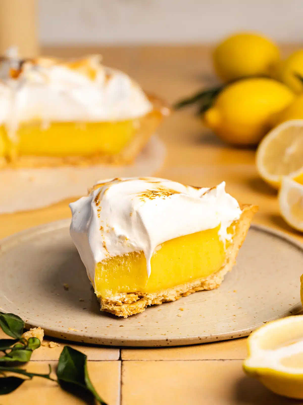 a slice of vegan lemon meringue pie on a ceramic plate with a spoonful taken from it showing the smooth and creamy consistency.