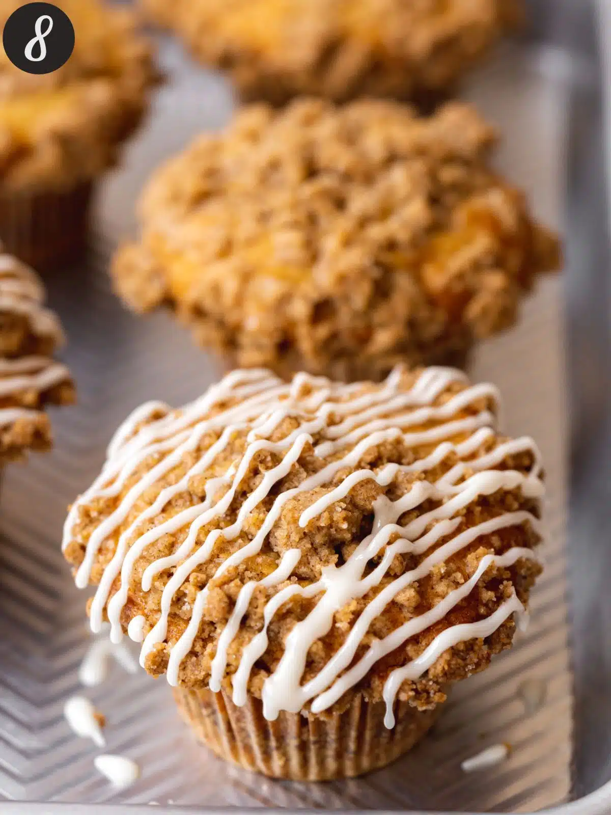 Baked and cooled cinnamon streusel muffins topped with a drizzle of glaze.