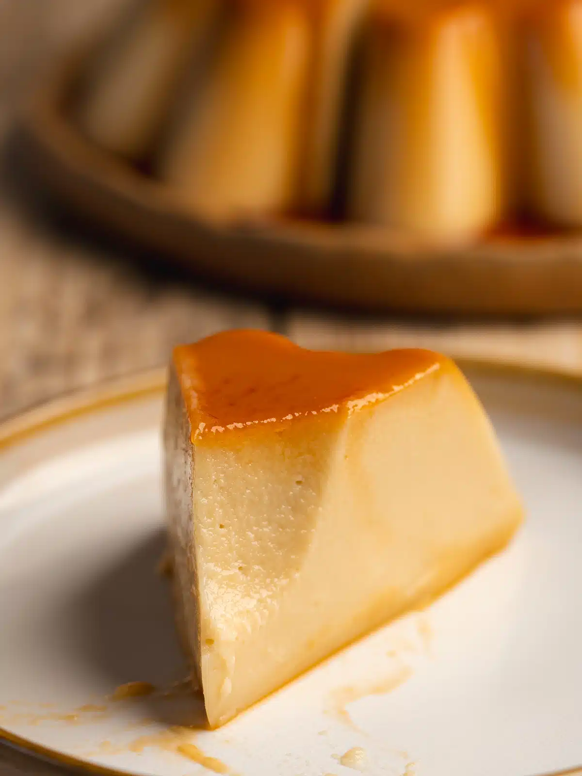 a slice of vegan flan on a ceramic plate with caramel on top and a spoonful removed showing the rich and creamy consistency.