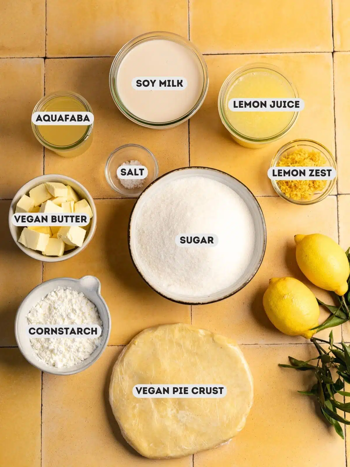 ingredients for eggless meringue lemon pie measured out in bowls on a yellow tiled surface with text overlay.