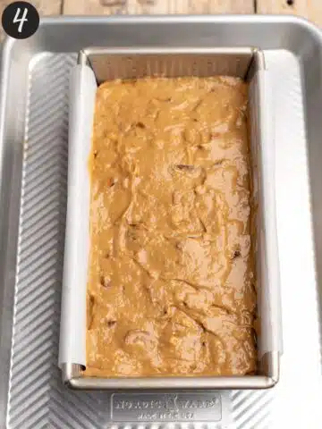 date and walnut cake batter smoothed out in a USA loaf pan.
