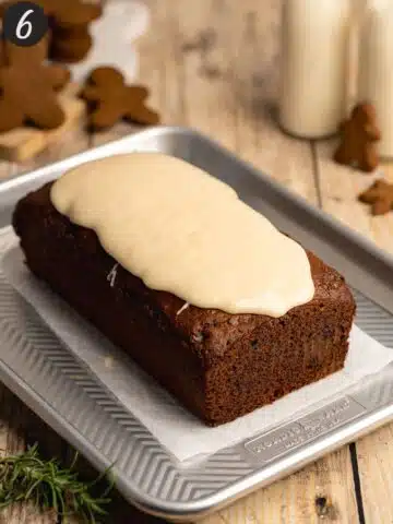 vegan gingerbread cake on a metal tray with cream cheese icing poured on top.