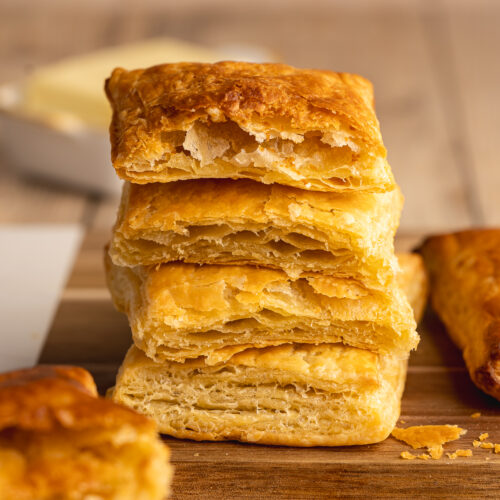 Stack of 4 baked pieces of vegan puff pastry from the side, showing the deliciously flaky layers.