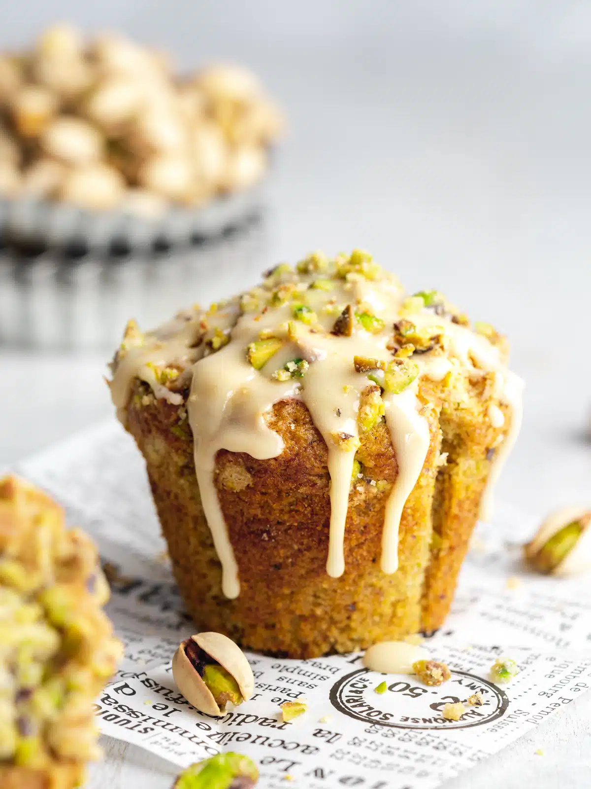 a pistachio muffin with pistachio crumble topping and vanilla glaze poured over the top.