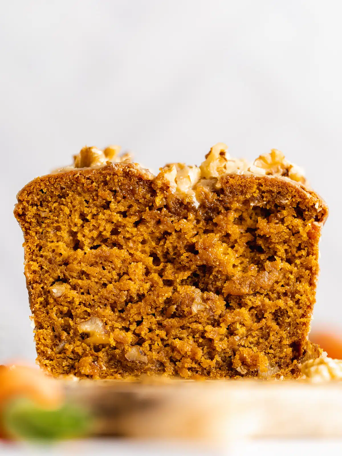 face on view of a carrot loaf cake with a slice cut away from it showing the fluffy and moist interior.