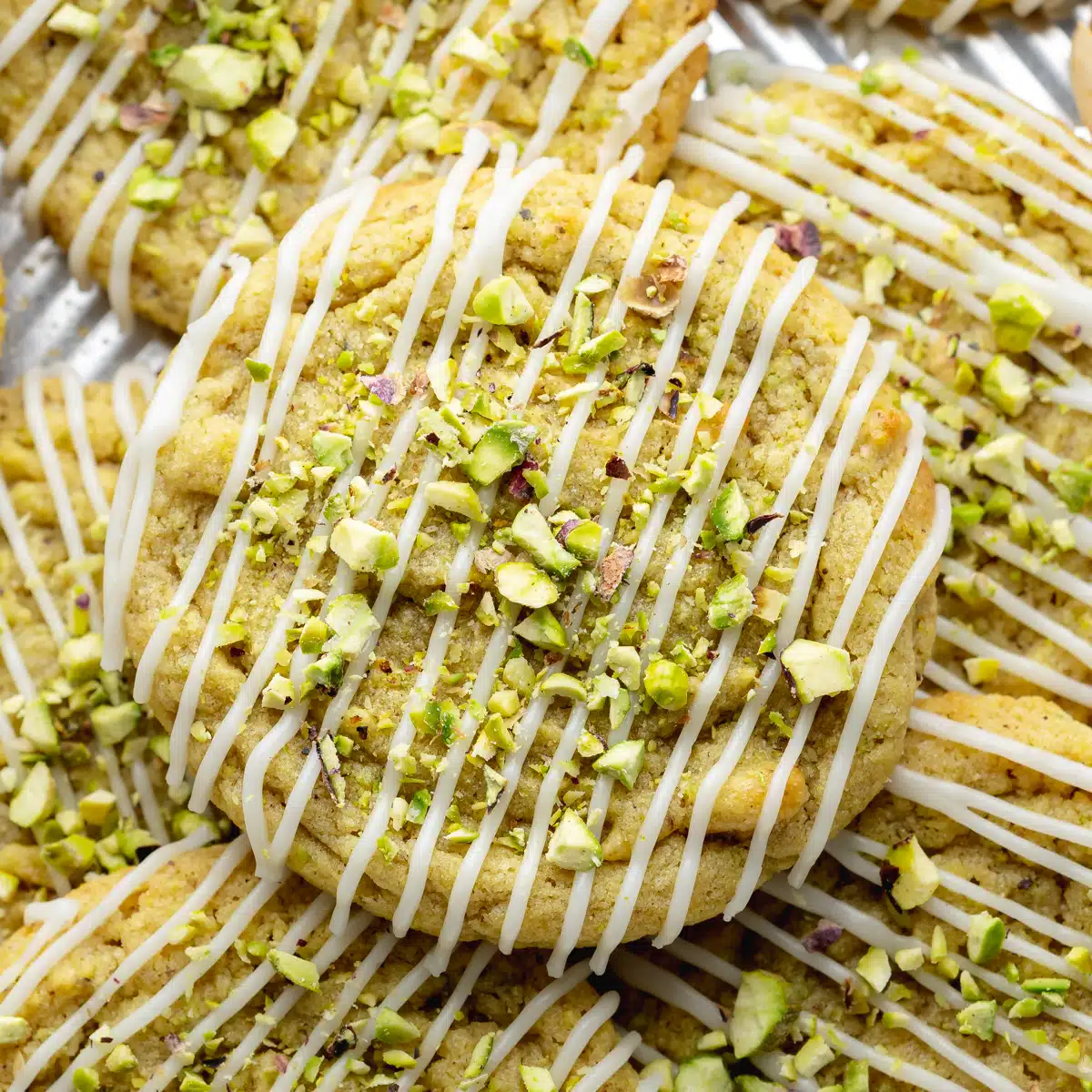 pistachio cookies with icing drizzled across them.