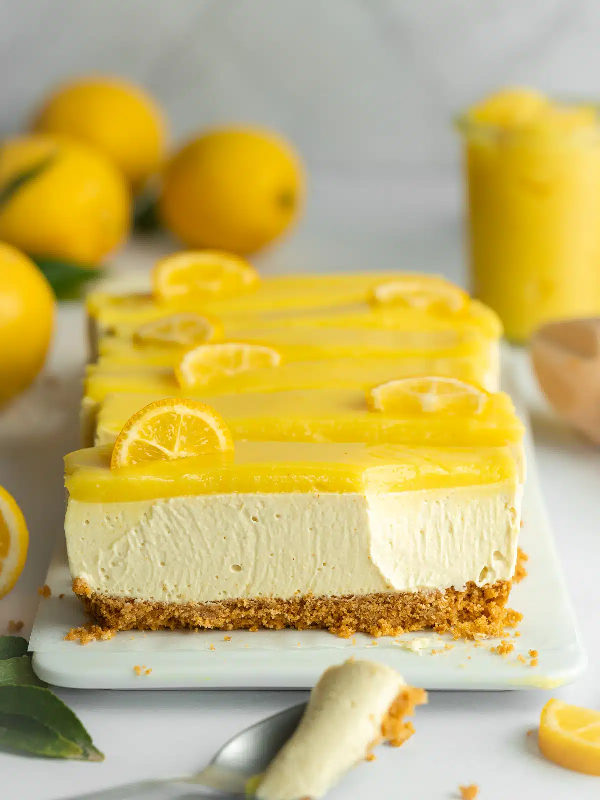 lemon cheesecake bars with a spoonful taken from one showing the creamy interior.
