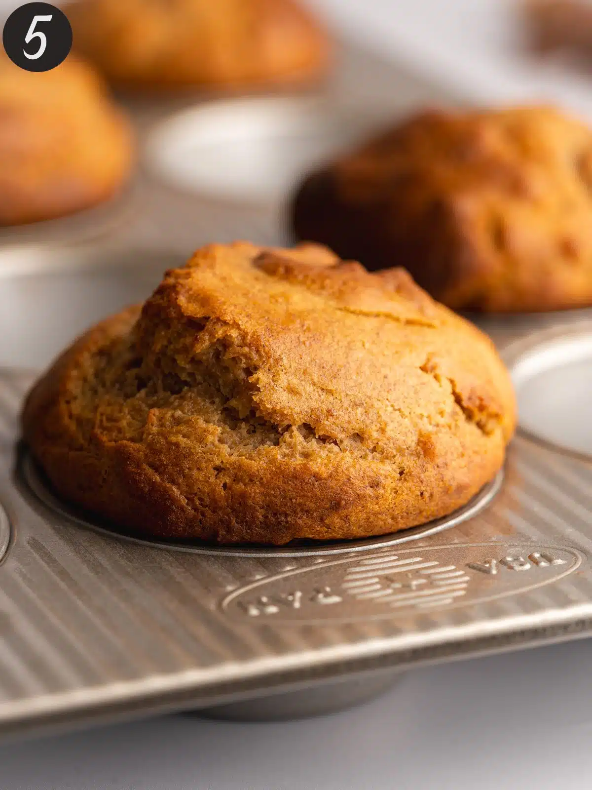 tall muffins in a muffin pan straight from the oven.