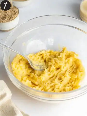 a large mixing bowl with a fork inside and mashed banana.