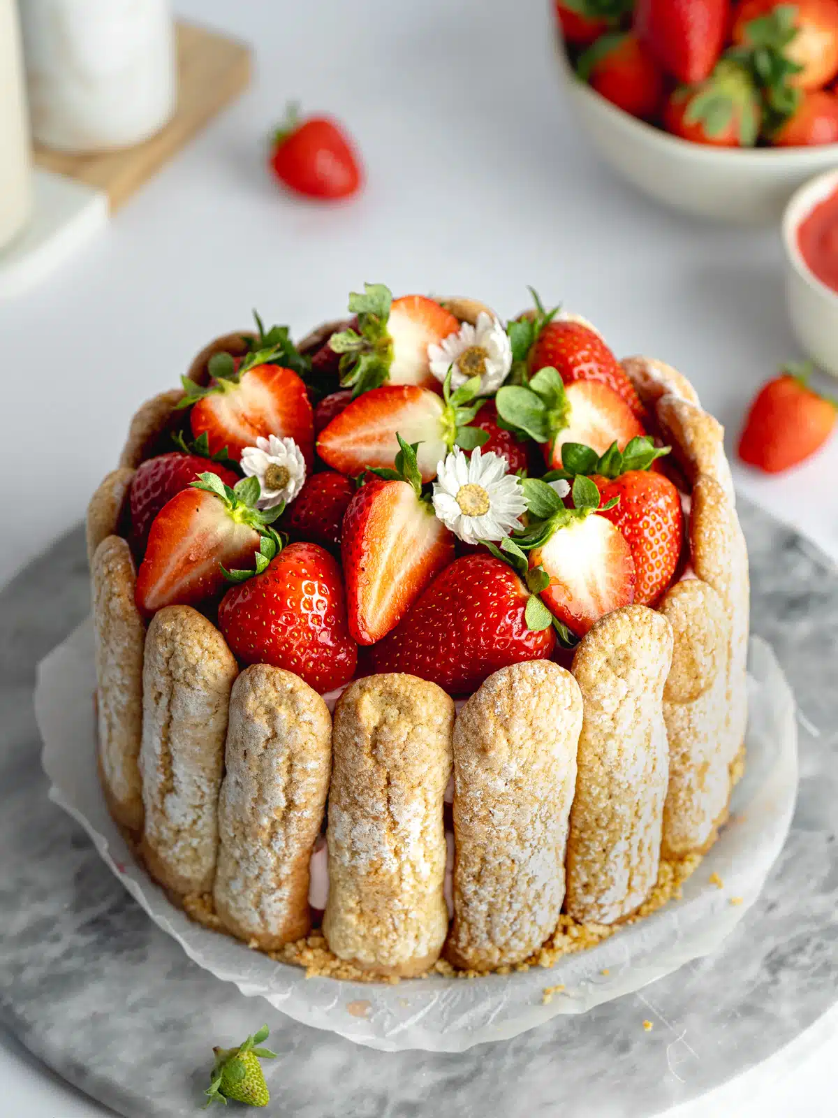 strawberry charlotte russe with fresh strawberries and ladyfingers on a marble board.