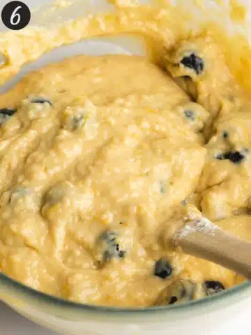 blueberry lemon cake batter folded together with a rubber spatula in a large bowl.