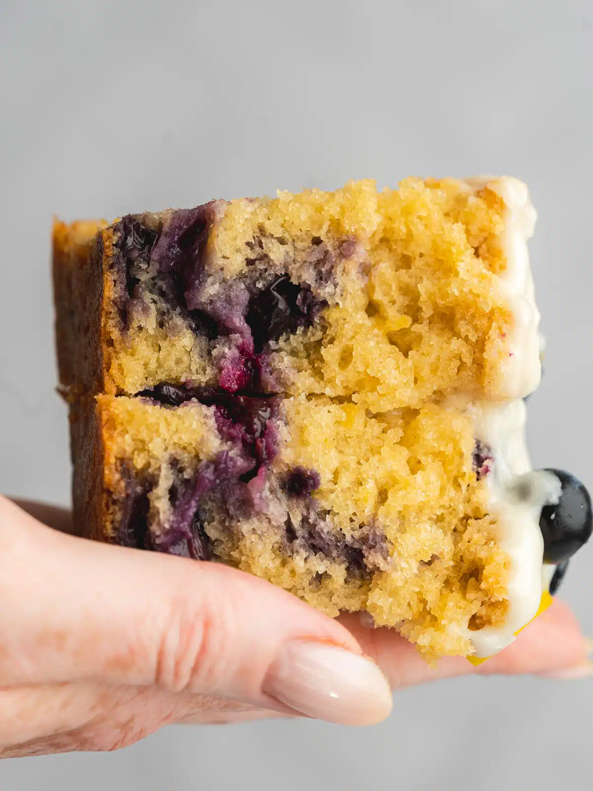 a loaf cake covered in icing with fresh blueberries on top.