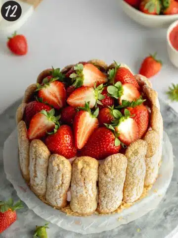 strawberry charlotte russe cake topped with fresh strawberries on a marble board.