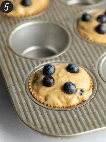 blueberry muffins in a muffin pan before baking with every second well left empty.