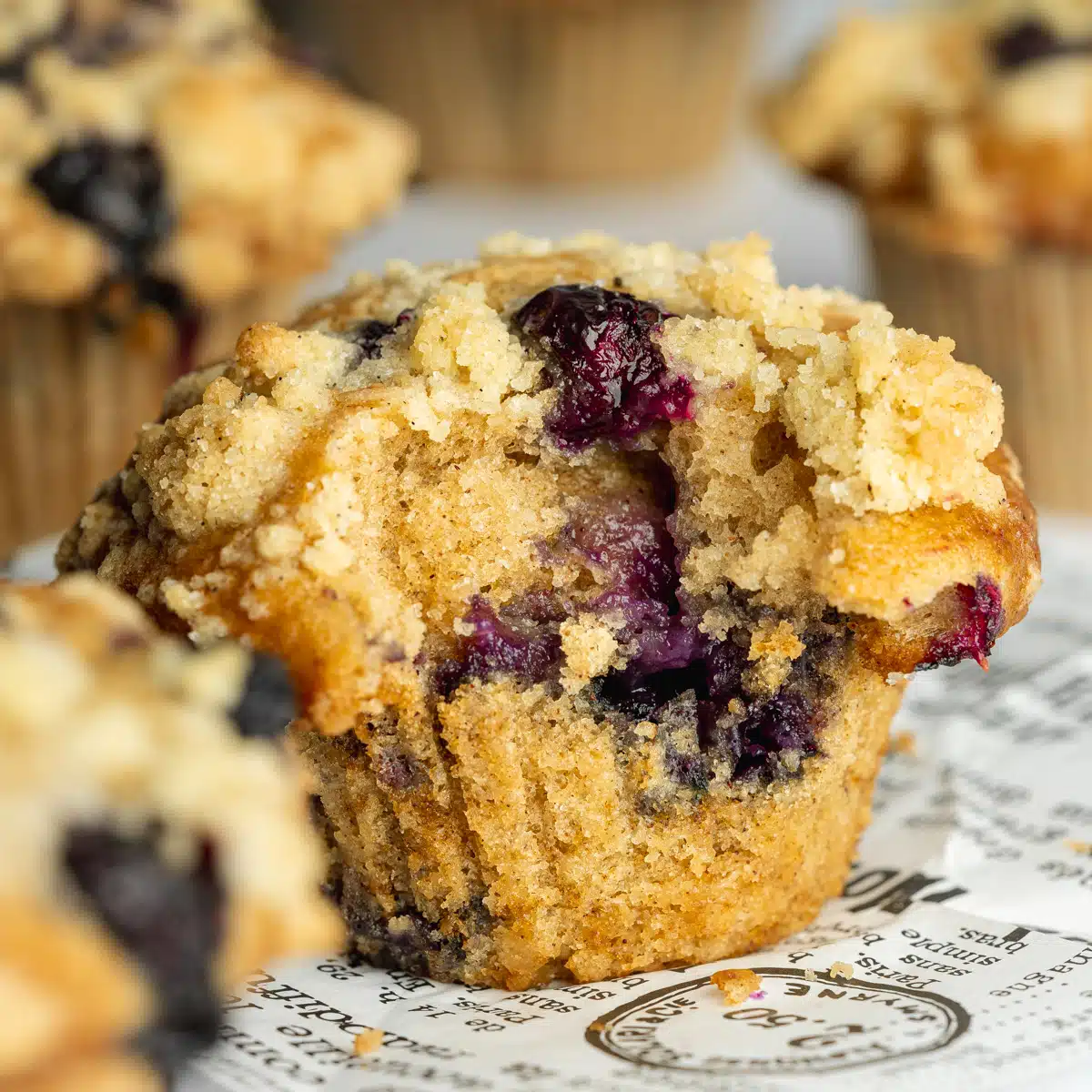 a bakery-style blueberry muffin with streusel topping and a bite taken out of it.