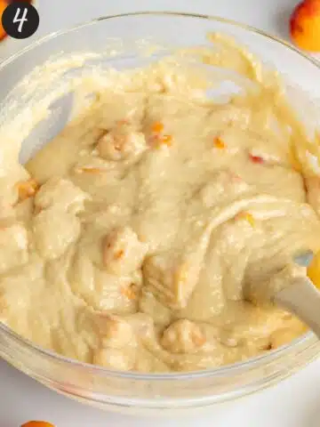 cake batter in a large bowl with apricot pieces mixed in.