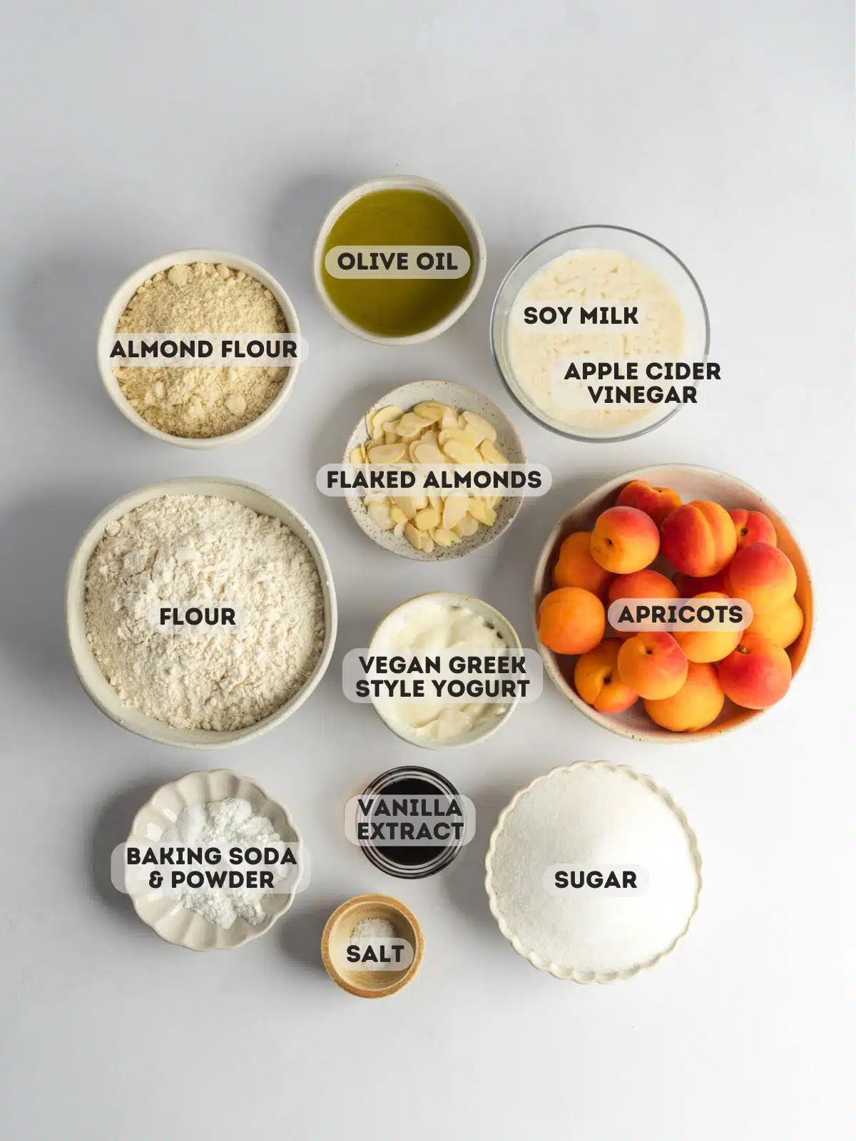ingredients for vegan apricot bread measured out in bowls on a gray surface.