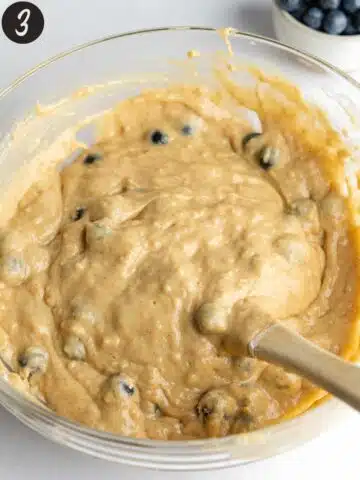 muffin batter with fresh blueberries folded through using a rubber spatula.