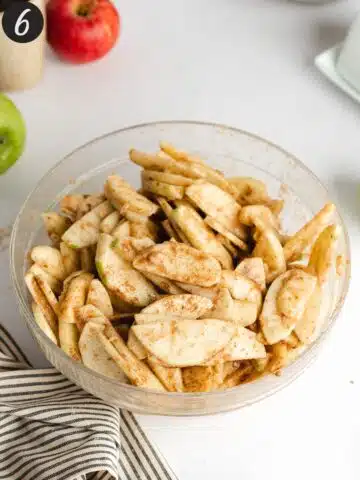 a mixing bowl with apple slices coated in cinnamon, flour and vanilla.